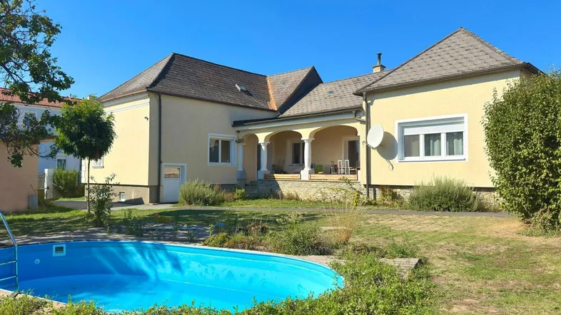 Großzügiges Anwesen mit einem einladenden Pool und weitläufigem Garten unter blauem Himmel.