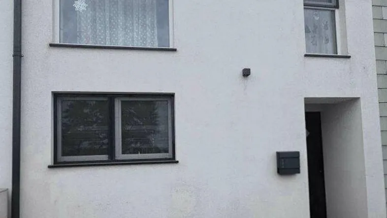 Moderne Hausfassade mit Eingangsbereich und gepflasterter Zufahrt.