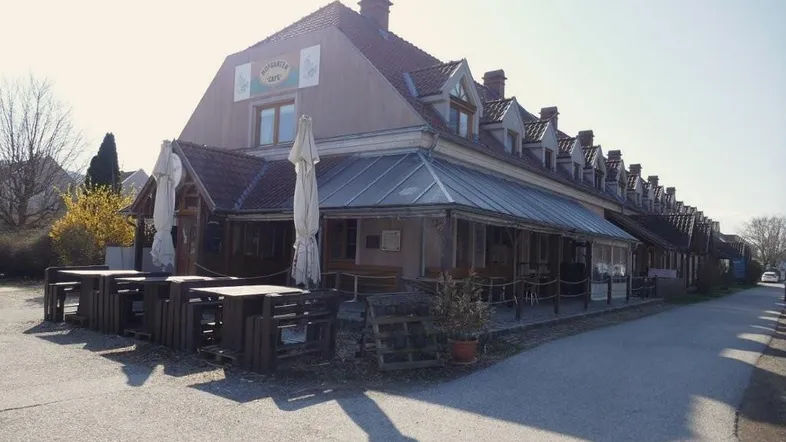 Traditionelles Gebäude mit Giebeldach und Außenbereich mit Tischen und Sonnenschirmen, ideal für ein Café.