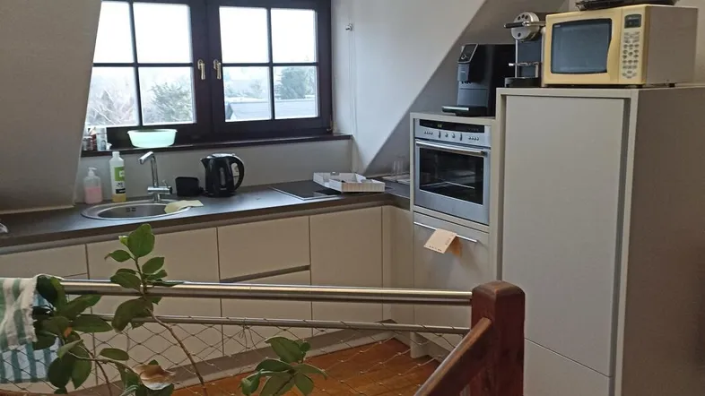 Dachgeschossküche mit Fenster, Einbaugeräten und Blick auf den unteren Bereich, ausgestattet mit modernen Elementen.
