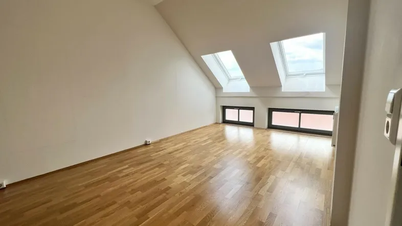 Helles Dachgeschosszimmer mit Holzparkettboden und mehreren Dachfenstern, ideal als Wohn- oder Schlafbereich.