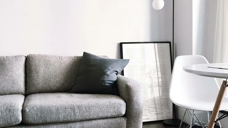 Helles Wohnzimmer mit modernem grauem Sofa, Holztisch und dunklem Holzboden in minimalistischem Design.