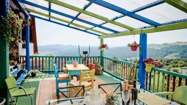 Bunte Terrasse mit Bergblick, überdacht und mit Esstisch für Mahlzeiten im Freien.