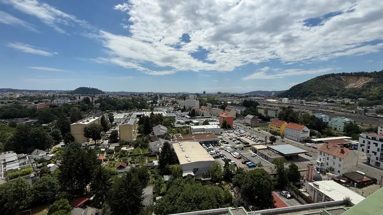 Panoramablick über die Stadt mit Wohn- und Gewerbegebieten sowie einer Bahnlinie am Horizont.