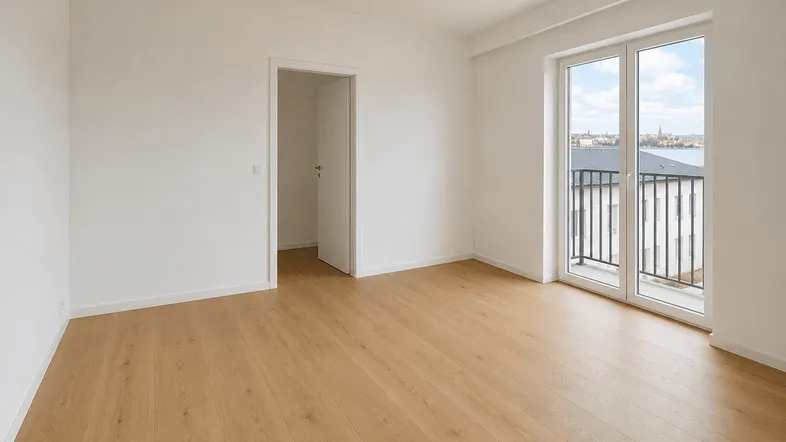 Helles, leeres Zimmer mit Parkettboden und Zugang zu einem Balkon mit Fernblick.