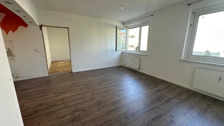 Heller Wohnbereich mit neuem Laminatboden und Blick ins Grüne, teilweise renovierungsbedürftig.