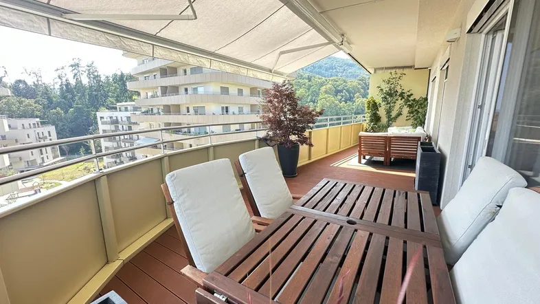 Geräumiger Balkon mit Esstisch, Stühlen und ausziehbarer Markise für Sonnenschutz.