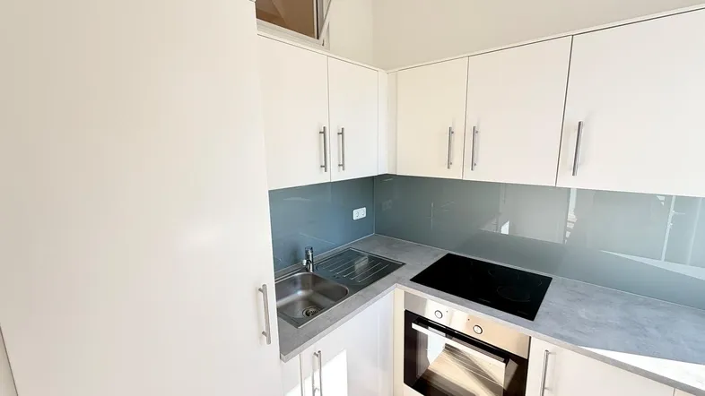 Moderne Einbauküche mit weißen Hochglanzschränken, Spüle und Kochfeld.