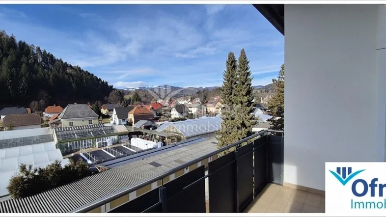 Panoramablick vom Balkon über die Stadt und die umliegende Berglandschaft unter blauem Himmel.