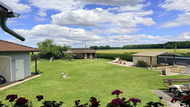 Weitläufiger Garten mit Rasenfläche, Sitzbereich und Blick auf die umliegende Landschaft.