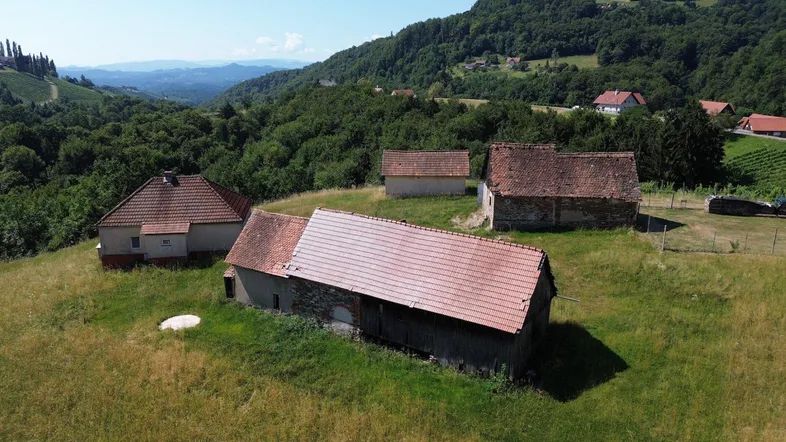 Luftaufnahme eines ländlichen Anwesens mit mehreren Gebäuden und Weinbergen in hügeliger Landschaft.