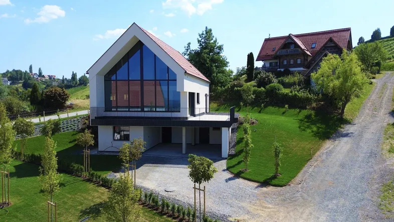 Modernes Haus mit großer Glasfassade und Satteldach in ländlicher Umgebung mit Weitblick.