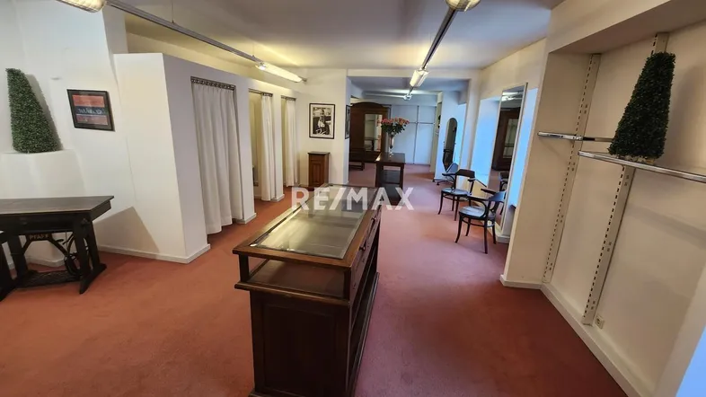 Geräumiger Ladenbereich mit rotem Teppichboden, weißen Wänden und Deckenbeleuchtung, ideal für ein Geschäft.