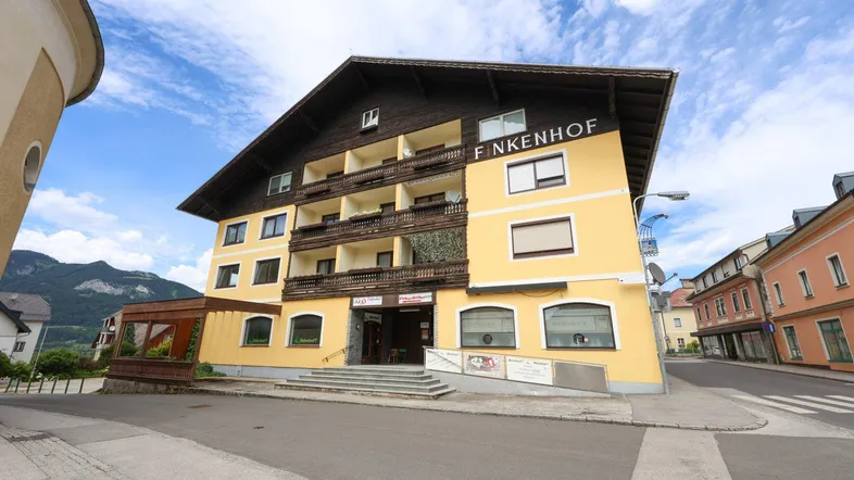 Gelbes Gebäude mit traditionellem Dach, Balkonen und einer Rampe am Eingangsbereich.