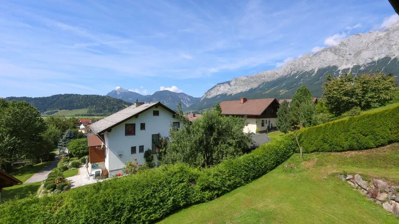 Weitläufiger Blick auf die umliegende Berglandschaft und benachbarte Häuser unter blauem Himmel.