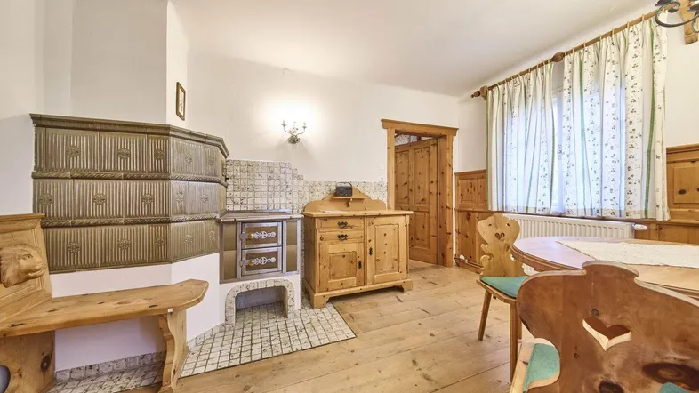 Traditionelles Wohnzimmer im alpinen Stil mit Kachelofen und rustikalen Holzmöbeln.