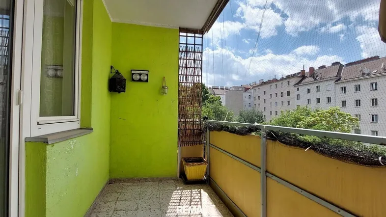 Heller Balkon mit leuchtend grünen Wänden und Blick auf die umliegenden Gebäude.
