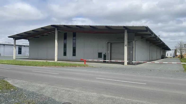 Industriegebäude mit Wellblechfassade, Laderampe und Zufahrt von der Straße aus gesehen.