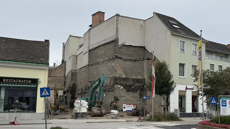 Baustelle mit teilweisem Abriss eines Gebäudes und Baugeräten in städtischer Umgebung.