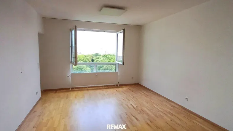 Helles Zimmer mit Holzboden und Blick ins Grüne, ideal als Wohn- oder Schlafzimmer.