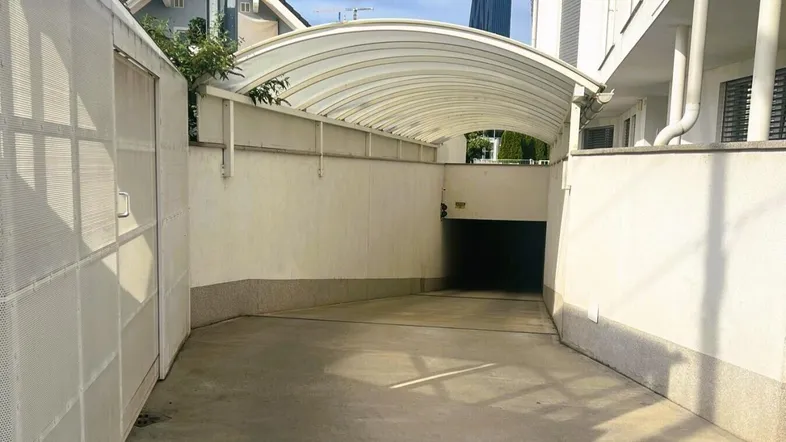 Überdachte Einfahrt zur Tiefgarage mit Rampe und Zugang zum Gebäude.