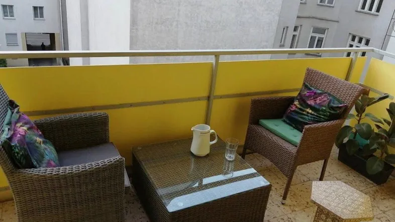 Gemütlicher Balkon mit Rattanmöbeln und Blick auf die umliegenden Gebäude.