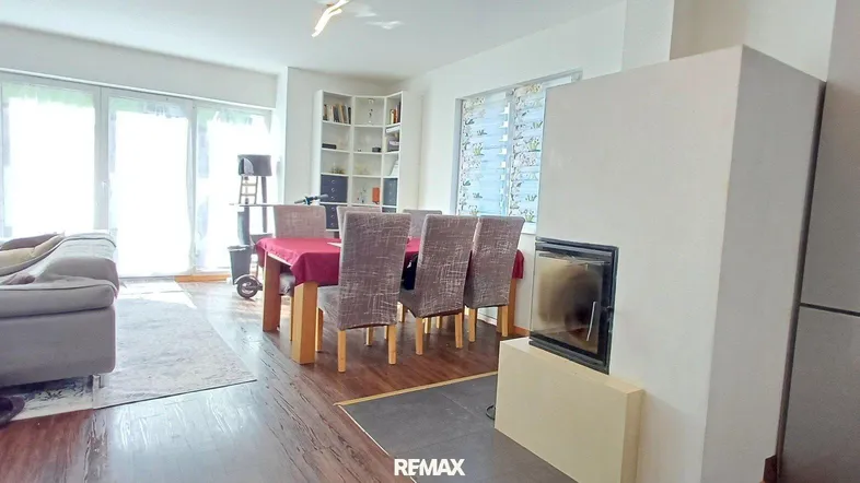 Heller offener Wohn- und Essbereich mit Kamin, Holzboden und Zugang zur Terrasse.