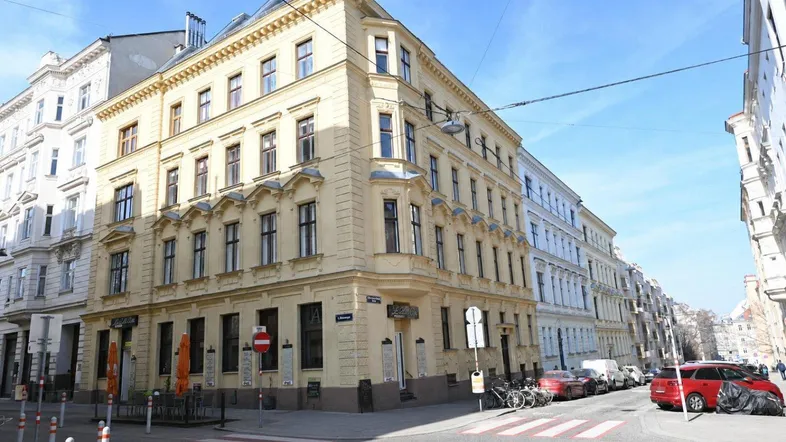 Historisches Eckgebäude in der Stadt mit klassischer Architektur und vielen Fenstern.