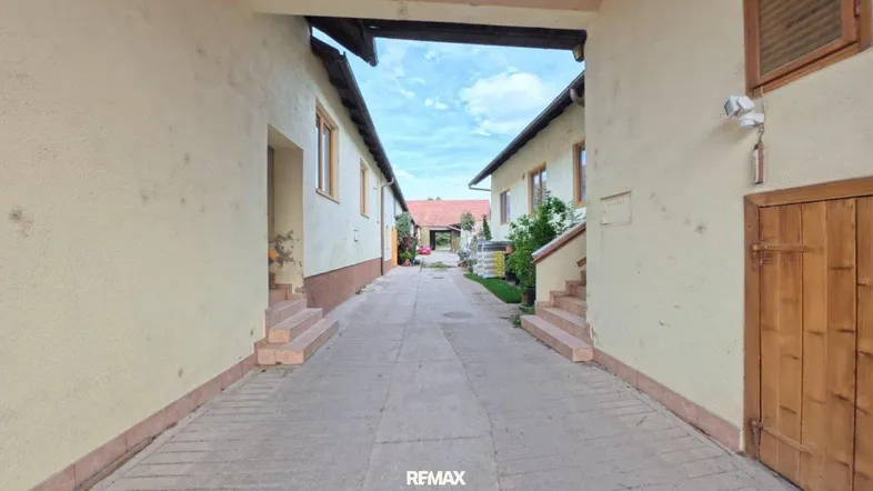 Schmaler gepflasterter Weg zwischen zwei Gebäuden, der zu einem Innenhof führt.