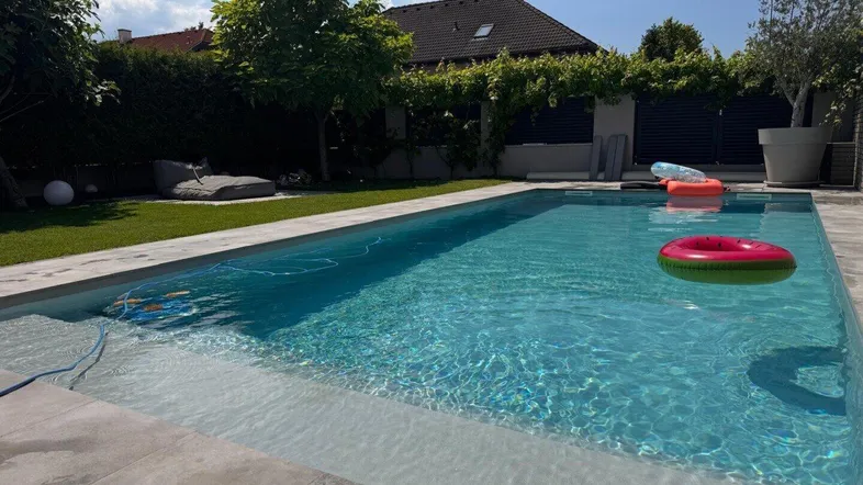 Großer Außenpool mit klarem Wasser und Liegefläche im sonnigen Garten.