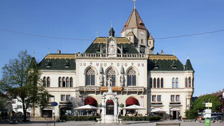 Historisches Gebäude mit aufwendiger Fassade und markantem Turm unter blauem Himmel.