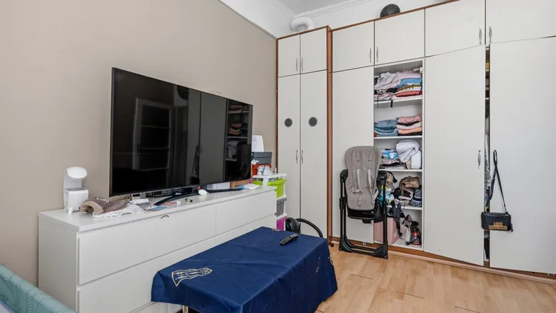 Schlafzimmer mit großem Kleiderschrank, Kommode, Fernseher und Babybett.