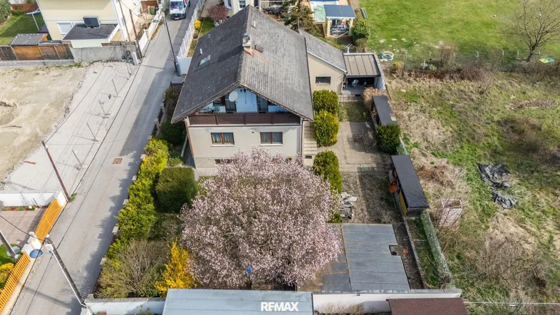 Luftaufnahme des Hauses mit blühendem Baum, Garten und umliegenden Grundstücken.