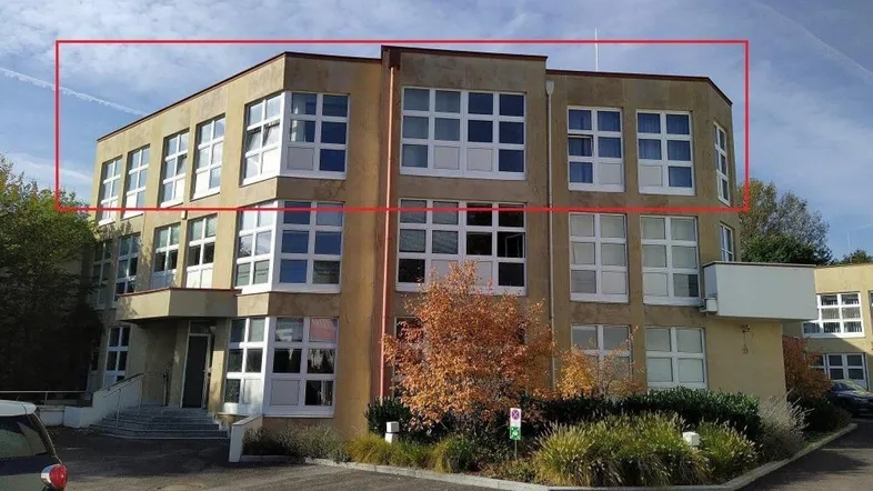 Modernes Bürogebäude mit vielen Fenstern und einer markanten Fassade in einem Gewerbegebiet.