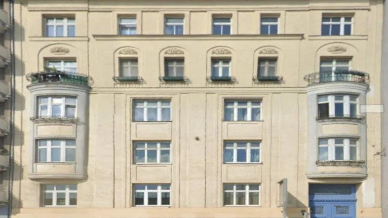 Klassische Fassade eines Mehrfamilienhauses mit Erkern und Balkonen in hellem Beige.