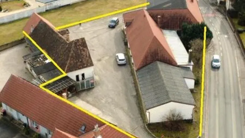 Luftaufnahme eines Grundstücks mit Gebäuden und gelber Umrandung in einer ländlichen Umgebung.