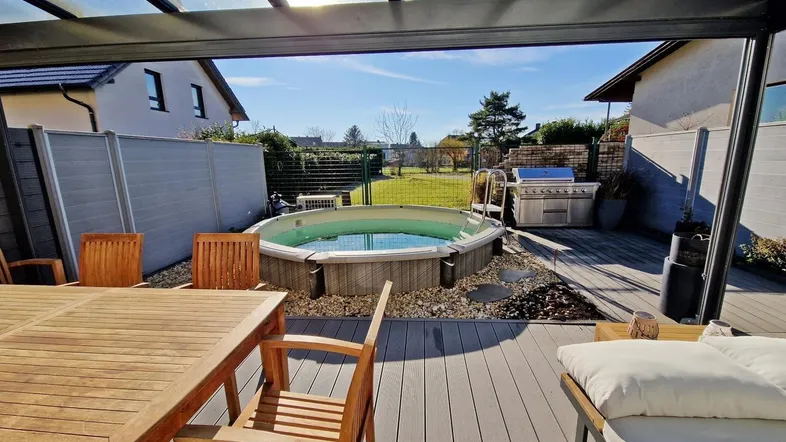 Sonnige Terrasse mit Whirlpool, Essbereich und Grillstation, ideal für Entspannung im Freien.