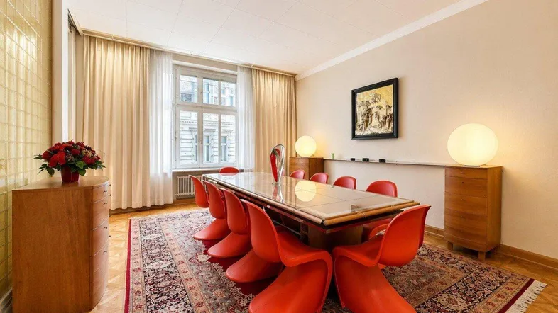 Geräumiger Essbereich mit großem Holztisch, modernen roten Stühlen und klassischem Teppichboden.