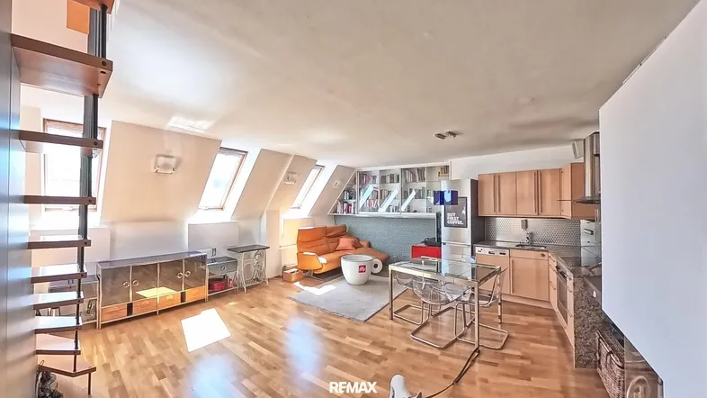 Helles Dachgeschoss-Apartment mit offener Küche, Wohnbereich und Holzfußboden.