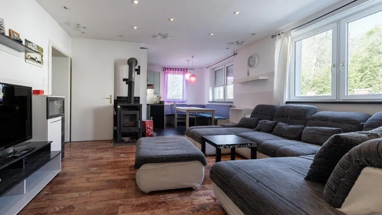 Geräumiges Wohnzimmer mit Kaminofen, großem Sofa und Blick in den Essbereich.