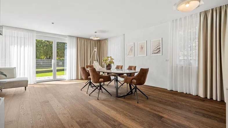 Heller Wohn- und Essbereich mit Holzboden, großen Fenstern und Zugang zum Garten.