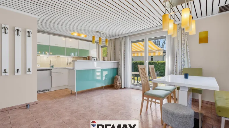 Offener Küchenbereich mit Essplatz, Zugang zur Terrasse und hellen Holzdecken.