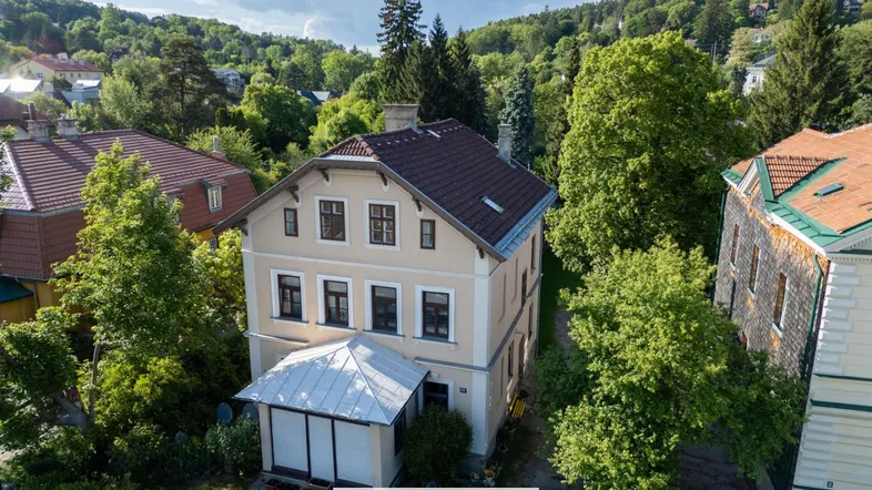 Luftaufnahme eines charmanten Hauses mit umliegender grüner Landschaft und Nachbargebäuden.