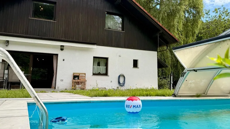 Außenansicht des Hauses mit Swimmingpool und teilweise überdachtem Bereich im Garten.
