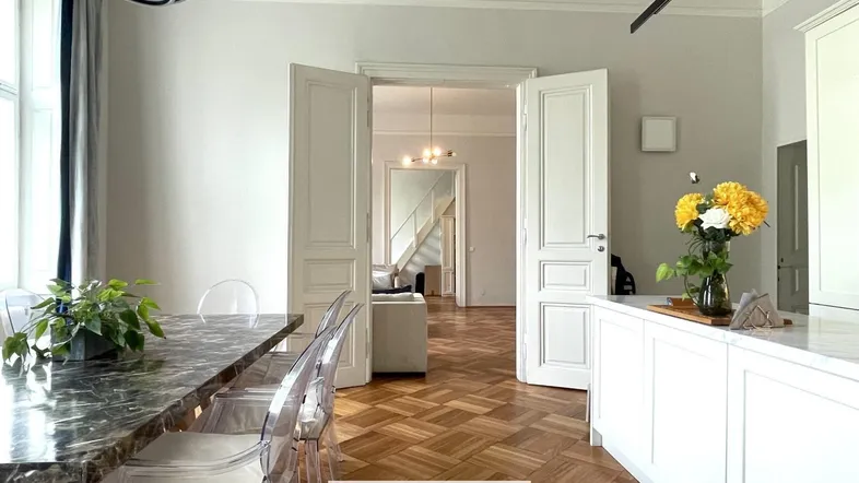 Heller Essbereich mit Marmortisch und Blick in das angrenzende Wohnzimmer mit Parkettboden.