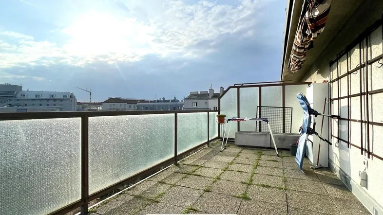 Geräumige Terrasse mit Glasgeländer und Blick auf die Stadt, ideal für Entspannung im Freien.