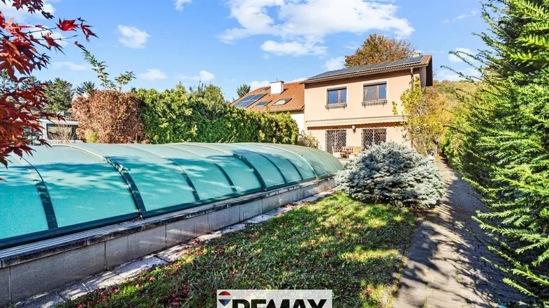 Gartenbereich mit überdachtem Pool und Blick auf das Haus in einer grünen Umgebung.