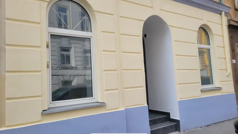 Historische Fassade eines Gebäudes mit Bogenfenstern und einem einladenden Eingangsbereich.