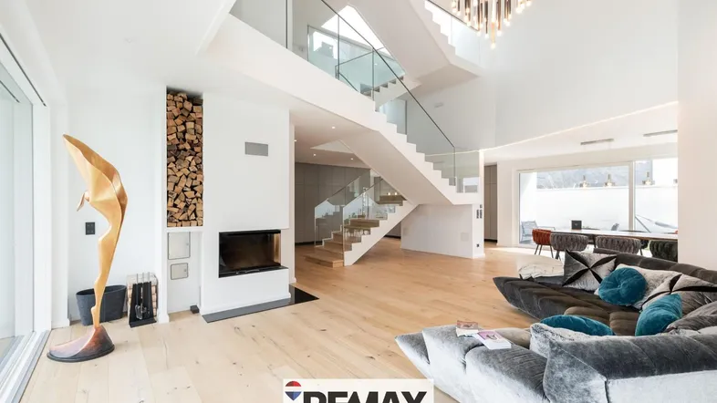 Großzügiges, lichtdurchflutetes Wohnzimmer mit modernem Kamin, hohen Decken und offener Treppe.