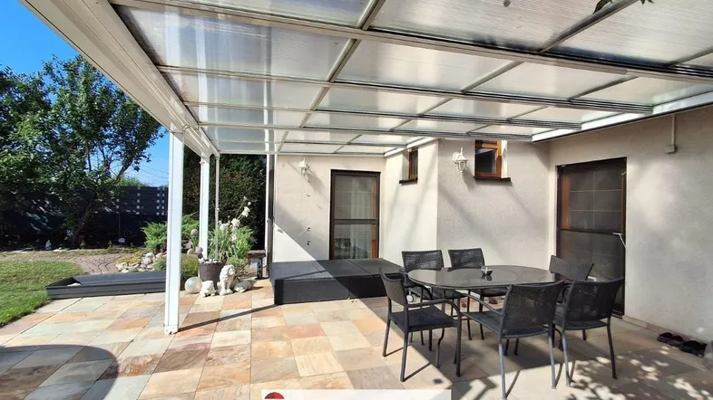 Große, überdachte Terrasse mit Sitzgelegenheiten und Blick auf den Garten, ideal für entspannte Stunden im Freien.